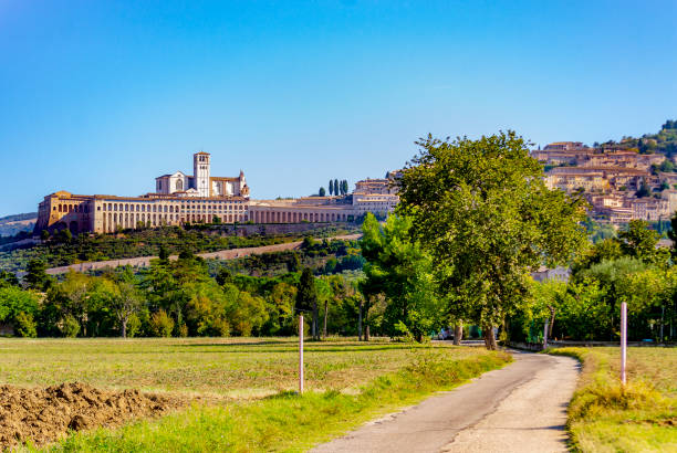 Country road to the Basilica and Sacro Convento di San Francesco in Assisi (Perugia, Umbria, Italy). ASSISI, PERUGIA, UMBRIA, ITALY - September 30, 2018: Panorama of the Basilica of the Sacro Convento di San Francesco, a World Heritage Site convento stock pictures, royalty-free photos & images