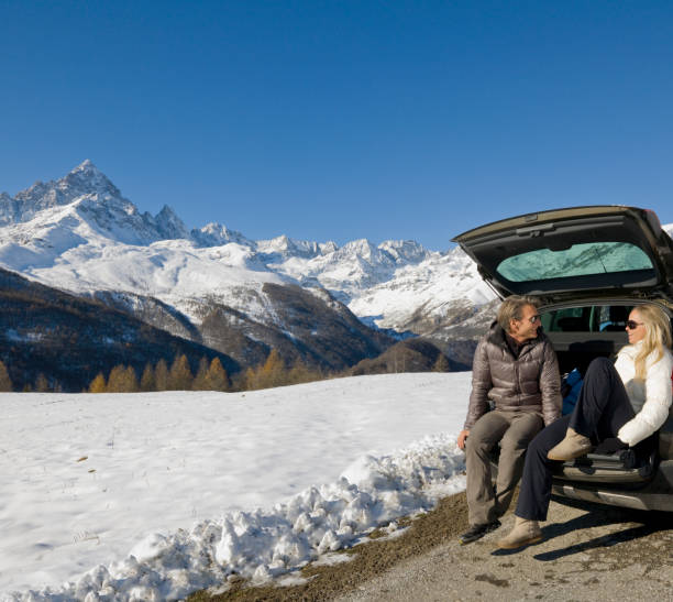 istock Couple sit on car tailgate, on mountain road 1069689088