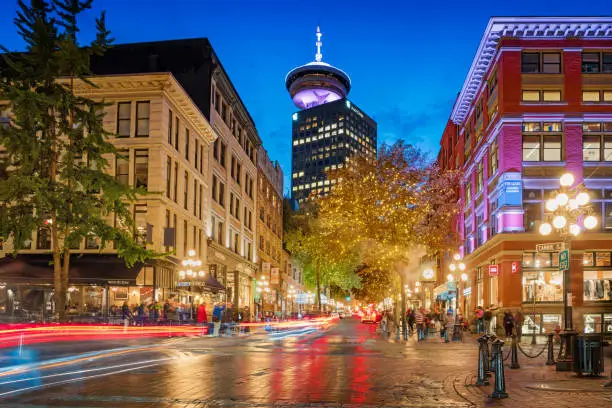 Long exposure stock photograph of Water street with the steam clock and the Vancouver Lookout in the background in Gastown, downtown Vancouver, British Columbia, Canada at twilight.