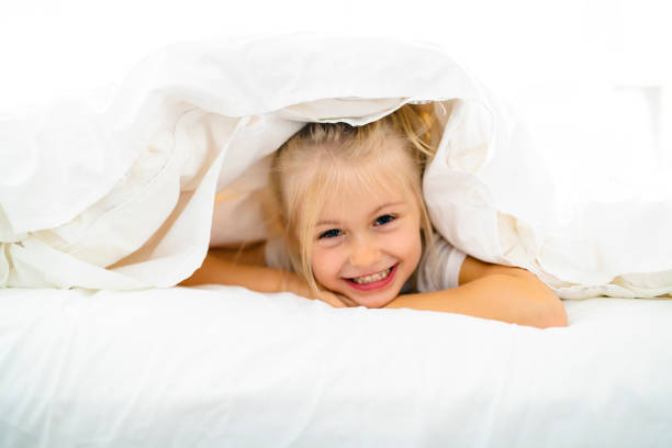 istock A Cheerful little girl in bed having fun 1069693220