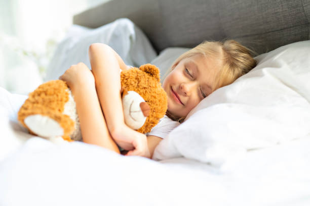 istock A little girl in bed sleeping and dreaming with teddy bear, 1069693404