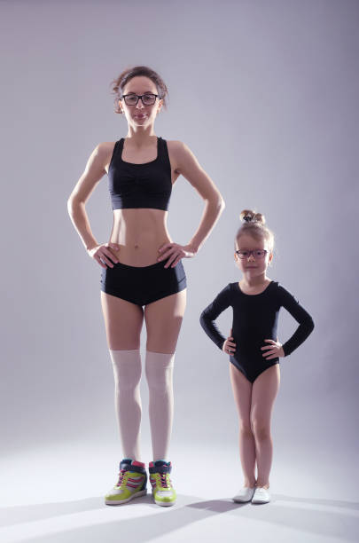 istock Mom and daughter in bathing suit dancing on a gray background. 1069697326