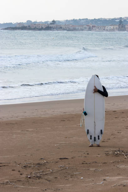 istock Man hiding behind a surfboard and showing shaka sign 1069700648