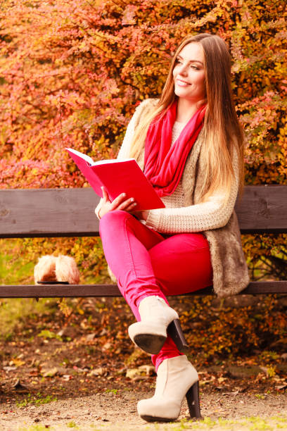 istock Woman relaxing in autumnal park reading book 1069710186