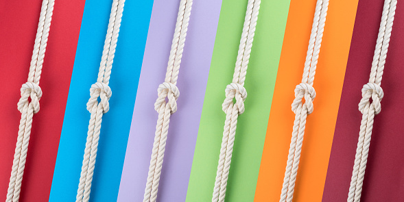 White ship ropes connected by reef knot on colored strips background. Abstract colorful composition