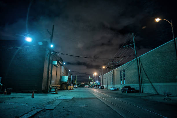 Industrial urban street city night scene with vintage factory warehouses and train tracks Industrial urban street city night scene with vintage factory warehouses and train tracks alley stock pictures, royalty-free photos & images