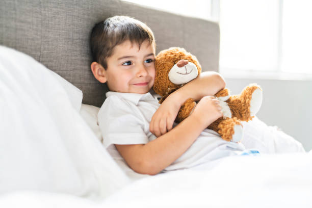 istock A Child lying in bed with a plush teddy bear 1069718472