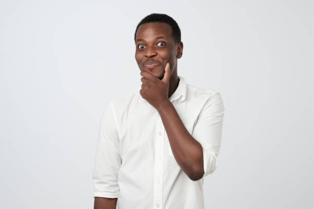 istock Sly cunning african man touching chin with finger and looking away. 1069721944