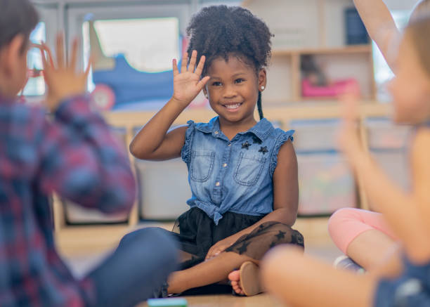 Children waving in kindergarten class Children smile and wave as part of a song or game in their kindergarten classroom. sign language stock pictures, royalty-free photos & images