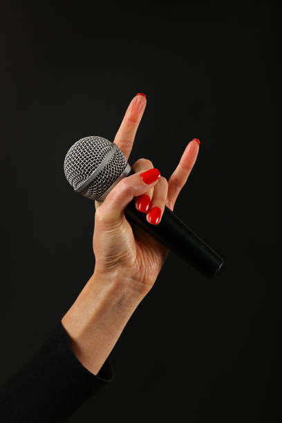 istock Close-Up Of Hand With Microphone Gesturing Over Black Background 1069722814