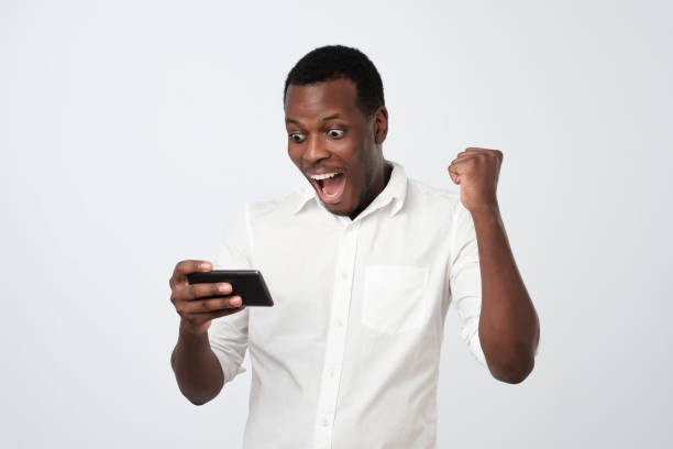 istock African man playing mobile game with shocked face. 1069722994