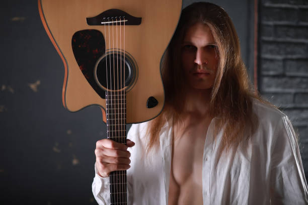 istock Young man with long hair with a guitar 1069723830