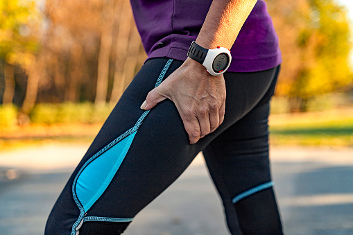 Cropped Image of Senior Woman Runner Hold Her Sports Injured Leg Outdoor. Injury From Workout Concept.