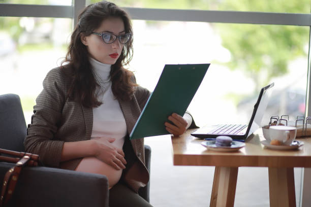 istock Pregnant woman working on computer in cafe 1069730412