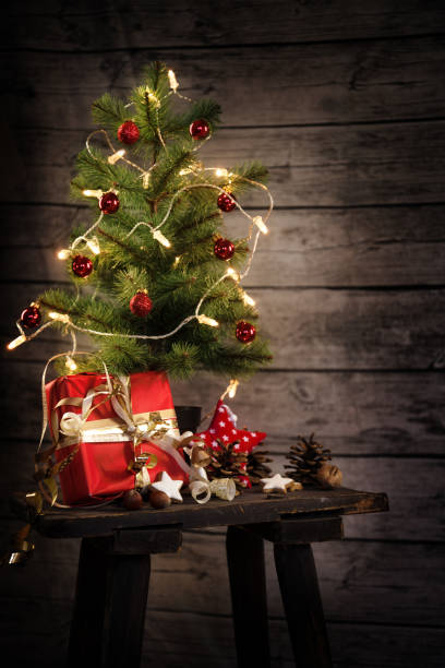 istock small artificial christmas tree with light chain, gift and decoration on an old stool in front of a rustic wooden wall, copy space, selected soft focus 1069734868