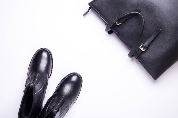 istock Woman accessory. Black stylish boots, black luxury leather bag on white background. Top view. Flat lay. 1069742582