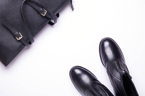 istock Woman accessory. Black stylish boots, black luxury leather bag on white background. Top view. Flat lay. 1069742592