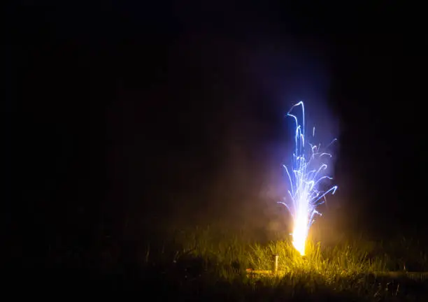 A roman candle streaming fire and flame finishing in a blue glow