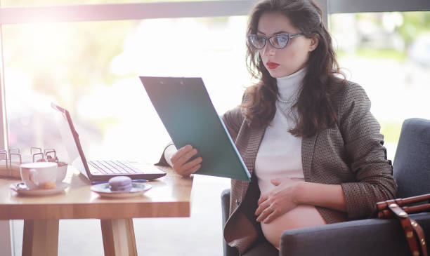 istock Pregnant woman working on computer in cafe 1069749828