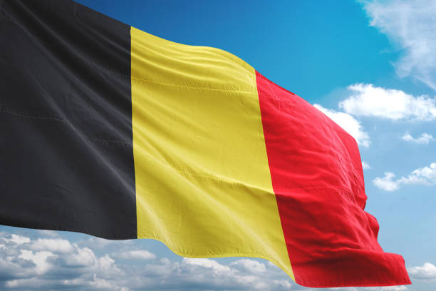belgië vlag zwaaien bewolkte hemelachtergrond - belgische vlag stockfoto's en -beelden