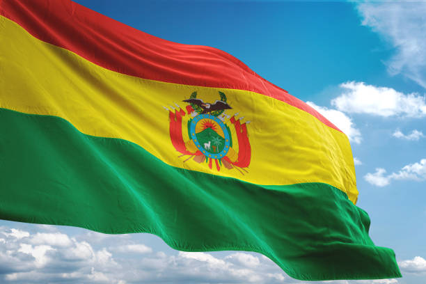 bandera de bolivia que agita el fondo de cielo nublado - bolivia fotografías e imágenes de stock