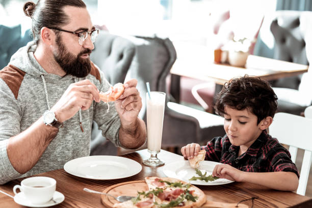istock Bearded father and cute funny son having fun eating pizza together 1069752928