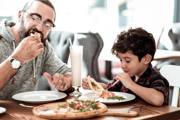 istock Funny beaming son feeling happy eating cheesy pizza with father 1069753310