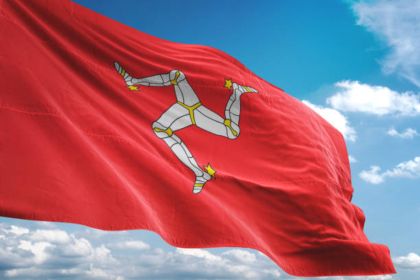istock Isle of Mann flag waving cloudy sky background 1069754040