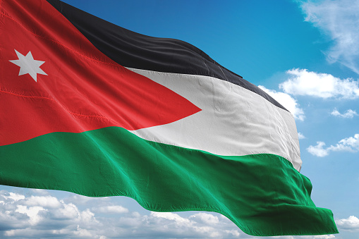 Bandera de Jordania que agita el fondo de cielo nublado photo