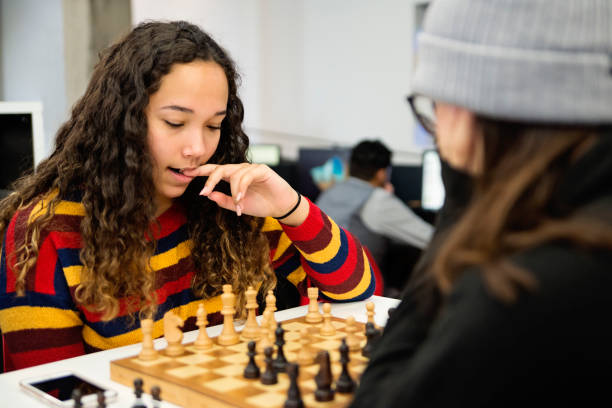 Young women student playing chess for relaxation in College library.