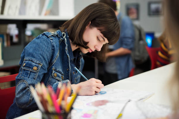 Young woman student coloring mandalas for relaxation in Colege library. stock photo