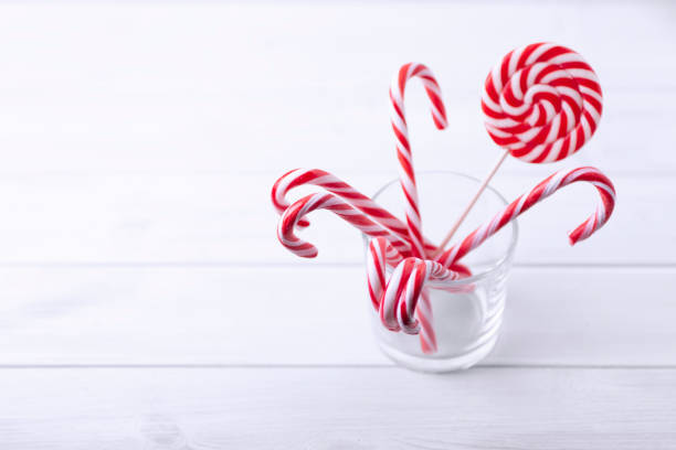 istock Glass with christmas candy canes on a white wooden table 1069764192