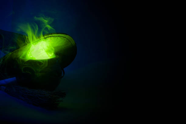 istock Happy Halloween, alchemy and magic spell potion concept with a pot or caldron boiling a green liquid with fumes and smoke coming out, next to a broomstick and a witch or wizard hat with copy space 1069764356