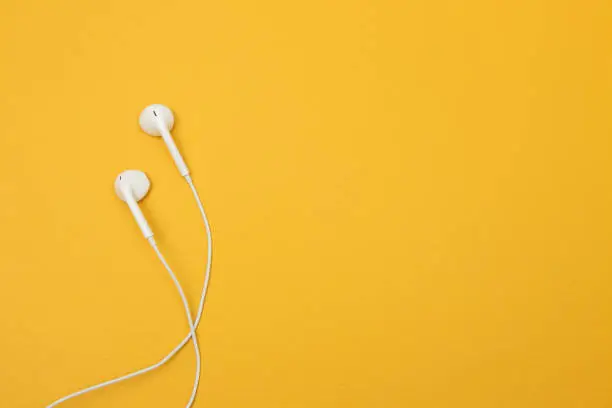 White earphones on yellow background, with space for text on the right.