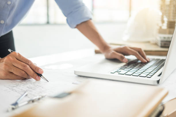 istock Midsection Of Architect With Blueprint Using Laptop On Desk 1069771280