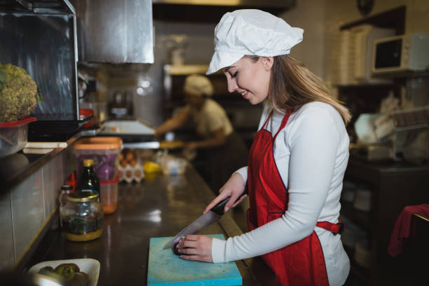 istock Young woman cutting ingredients and cooking in the restaurant kitchen 1069789036