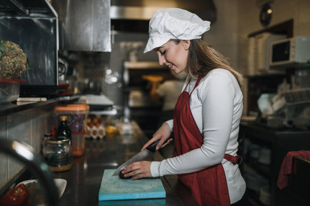 istock Young woman cutting ingredients and cooking in the restaurant kitchen 1069789078