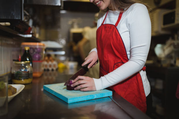 istock Young woman cutting ingredients and cooking in the restaurant kitchen 1069789080