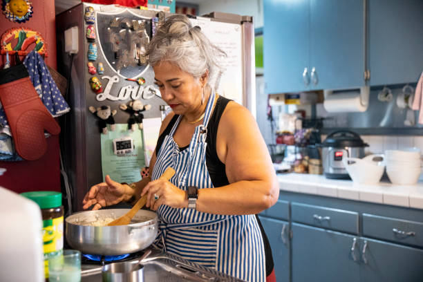 hispanic frau macht abendessen in küche - fett nährstoff stock-fotos und bilder