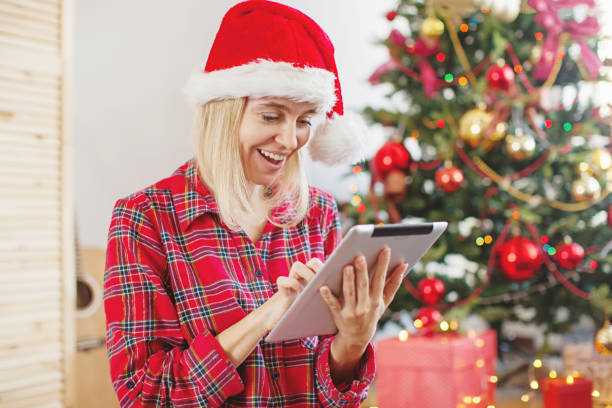 istock Woman using tablet in front of christmas tree 1069799754