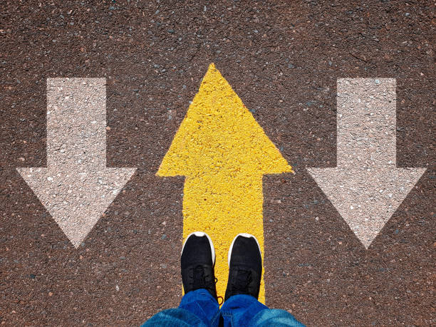 istock Opposing direction arrows on asphalt ground, personal perspective concept for finding your own way 1069800838