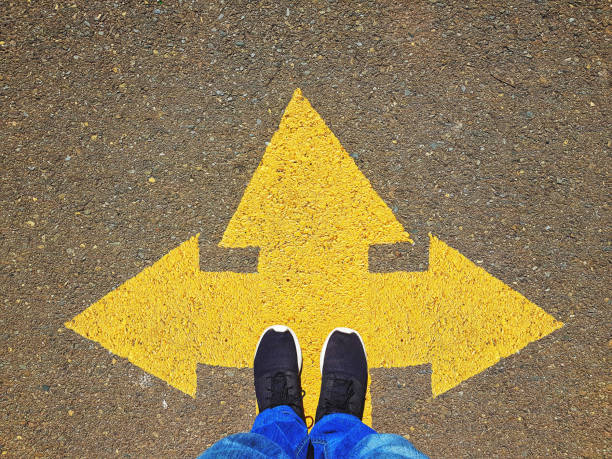 istock Opposing direction arrows on asphalt ground, personal perspective concept for finding your own way 1069800870