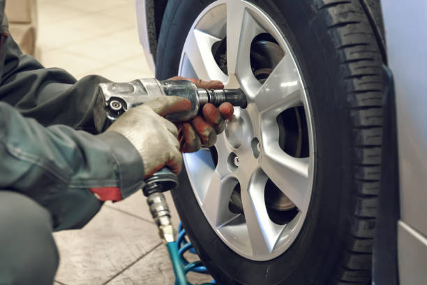 istock Replacing summer tires for winter using pneumatic wrench tool by mechanic worker after balancing wheels in car service garage shop 1069833774
