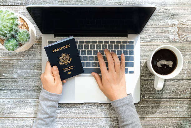 istock Person holding an American Passport while using a laptop 1069846170