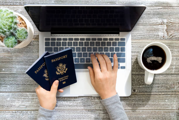 istock Person holding an American Passports while using a laptop 1069846188