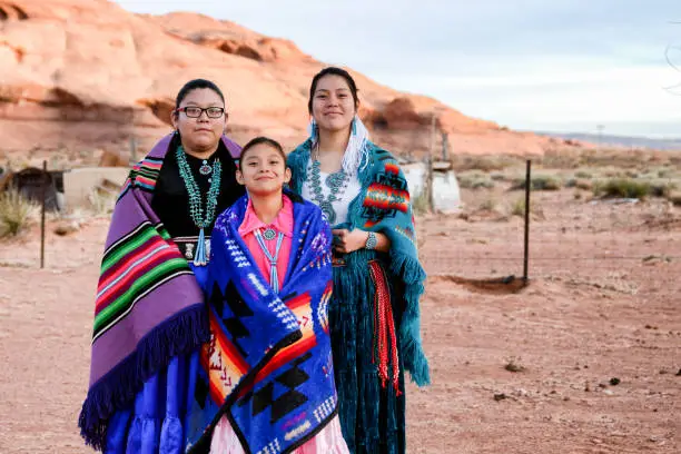 Three beautiful, proud and traditional Native Amerian Navajo sisters in traditional clothing posing outside in Monument Valley Arizona