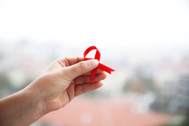 Aids Awareness campaign. Female hands holding red AIDS awareness ribbon stock photo