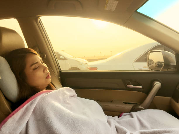 A young woman napping in the passenger seat during a road trip