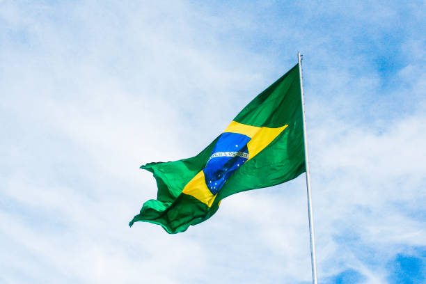 Flag of Brazil flying with blue sky stock photo