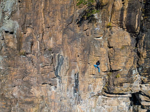 Aerial view of a young man rock climbing in an extreme location in the mountains of Japan